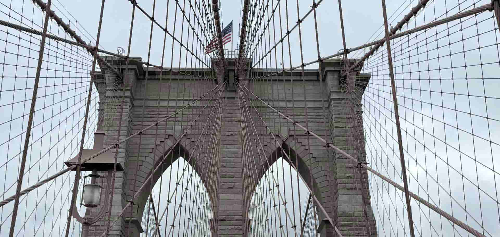 Close up of the gothic stone arches and suspension network of the historic Brooklyn Bridge.