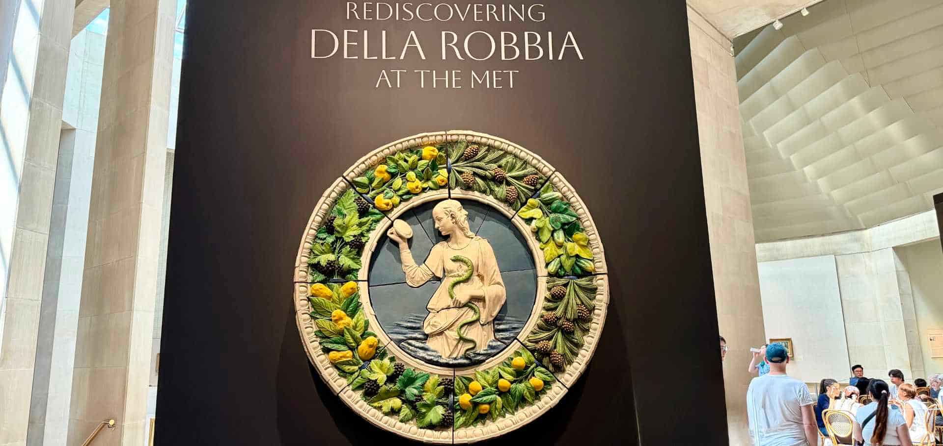 Exhibition sign featuring a vibrant Della Robbia circular terracotta relief displayed on a dark wall inside the museum