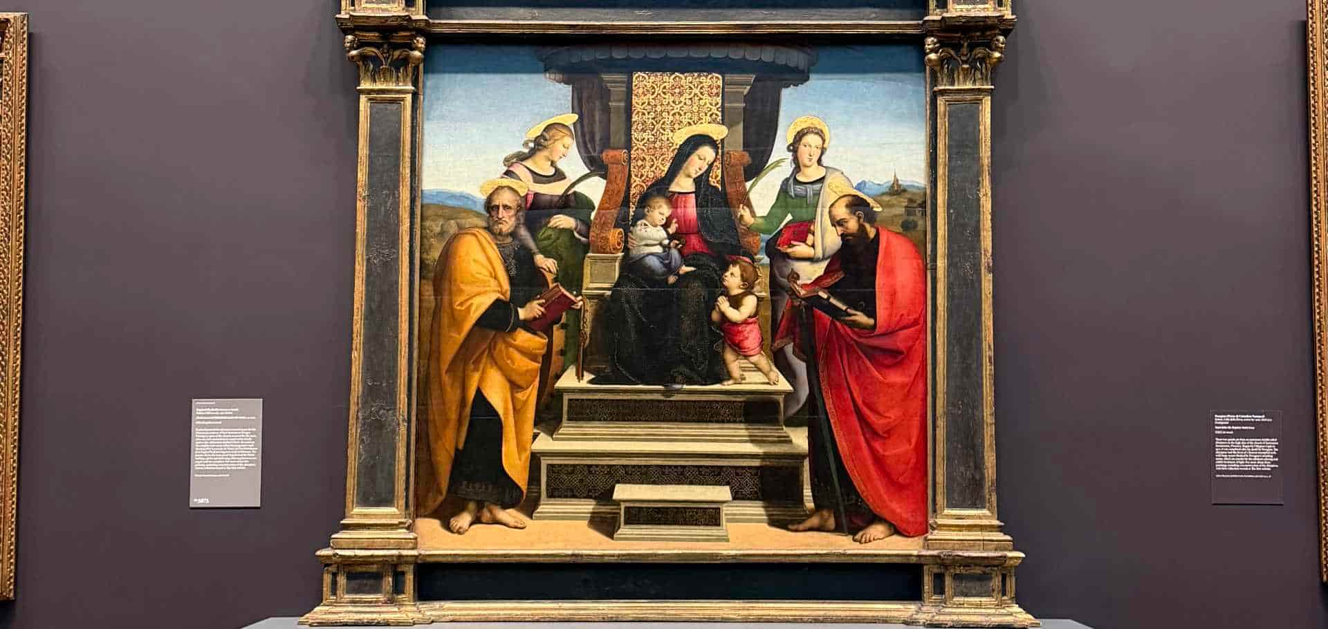 Religious Renaissance painting featuring a Madonna and child enthroned with saints.
