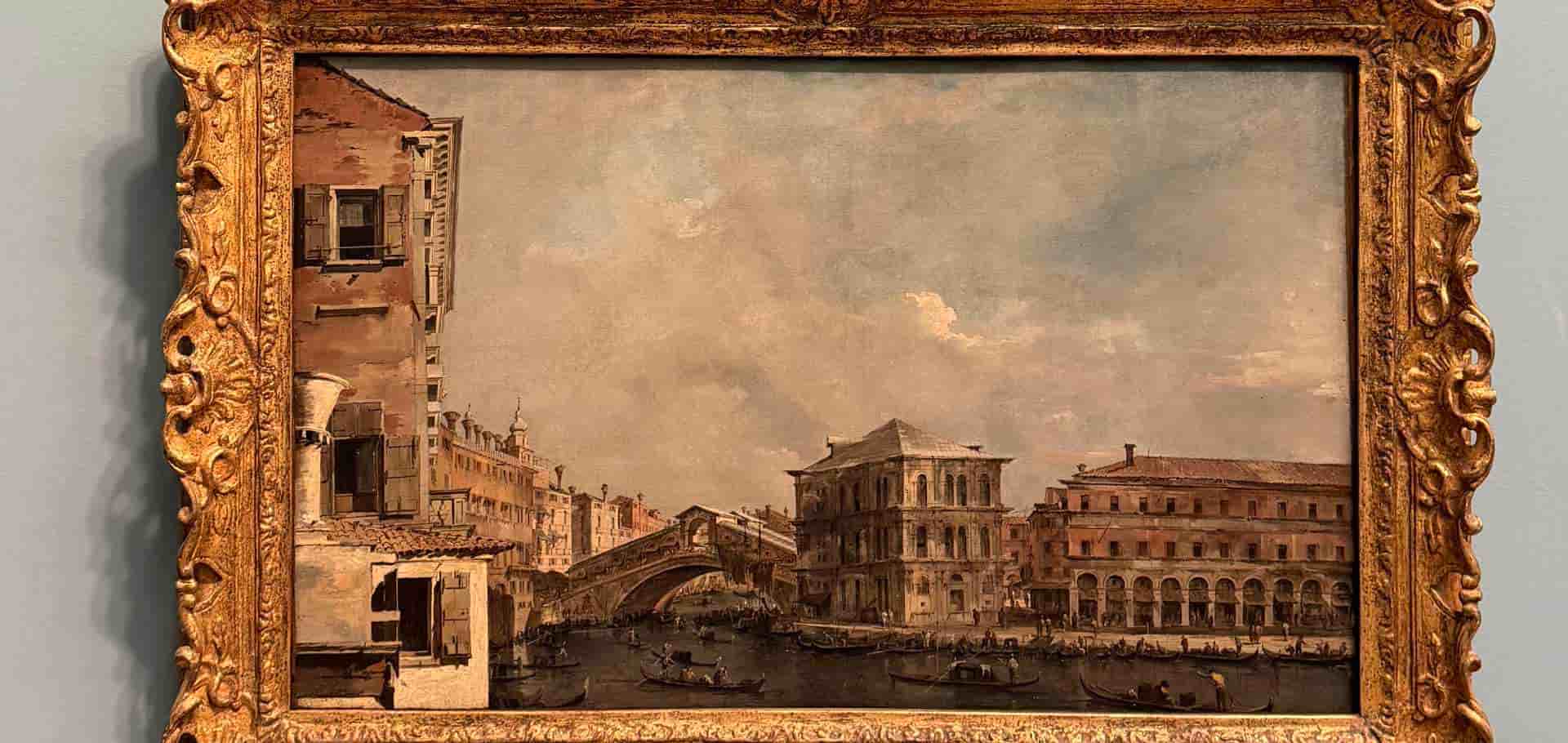 Detailed Venetian canal scene painting framed in an ornate gilded wooden border.
