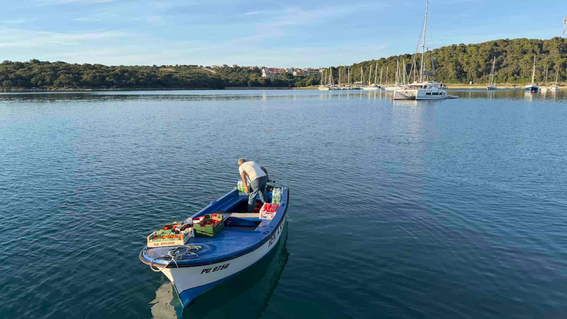 Suleiman tends to his cargo of fresh fruit and water bottles aboard his small blue motorboat