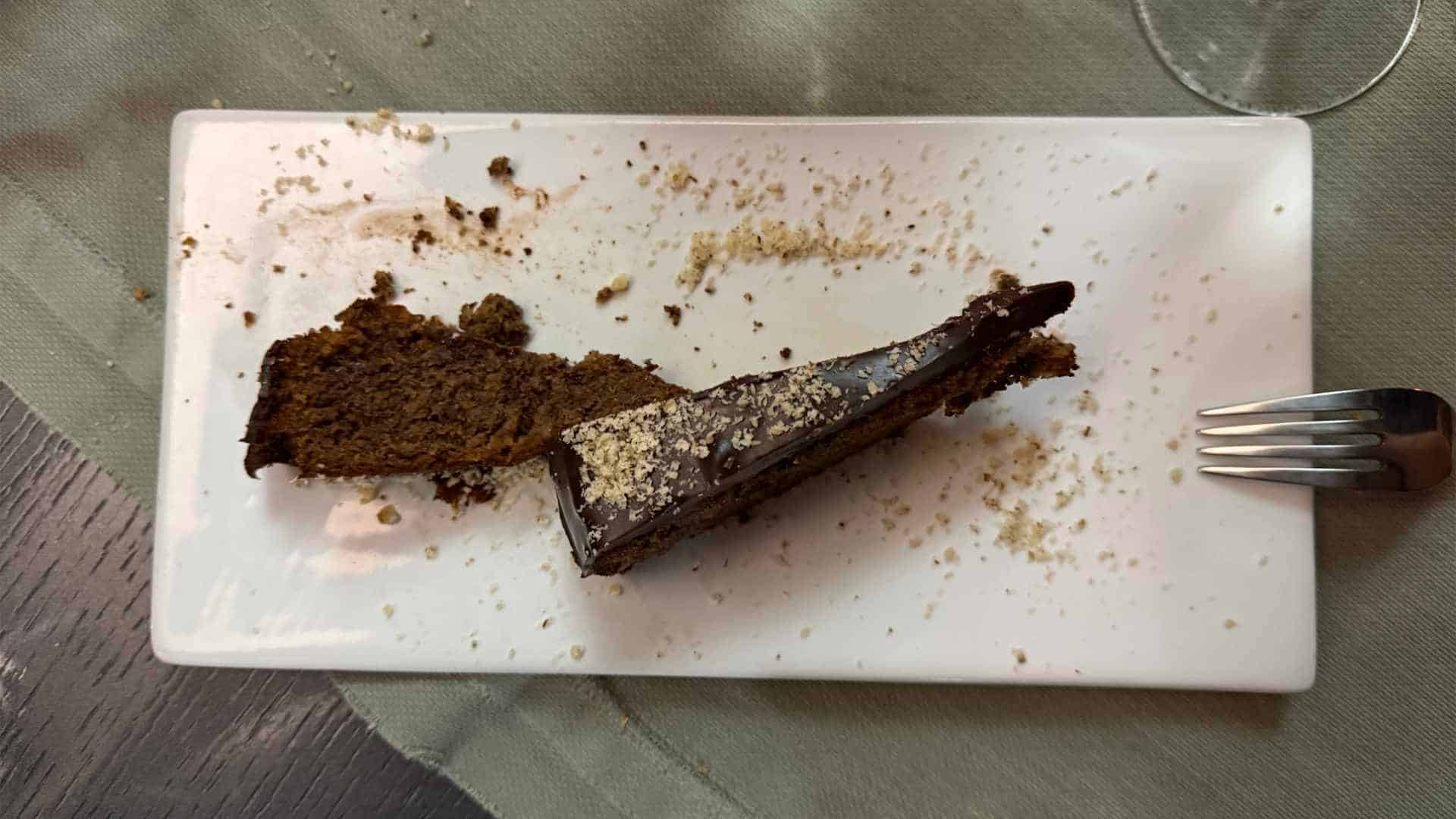 one slide of chocolate cake served with crushed almonds and sugar on top