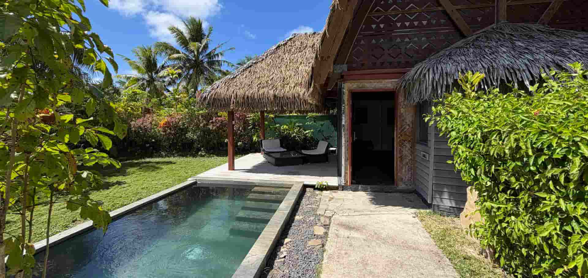 Private swimming pool and thatched eco-lodge bungalow exterior in Huahine.