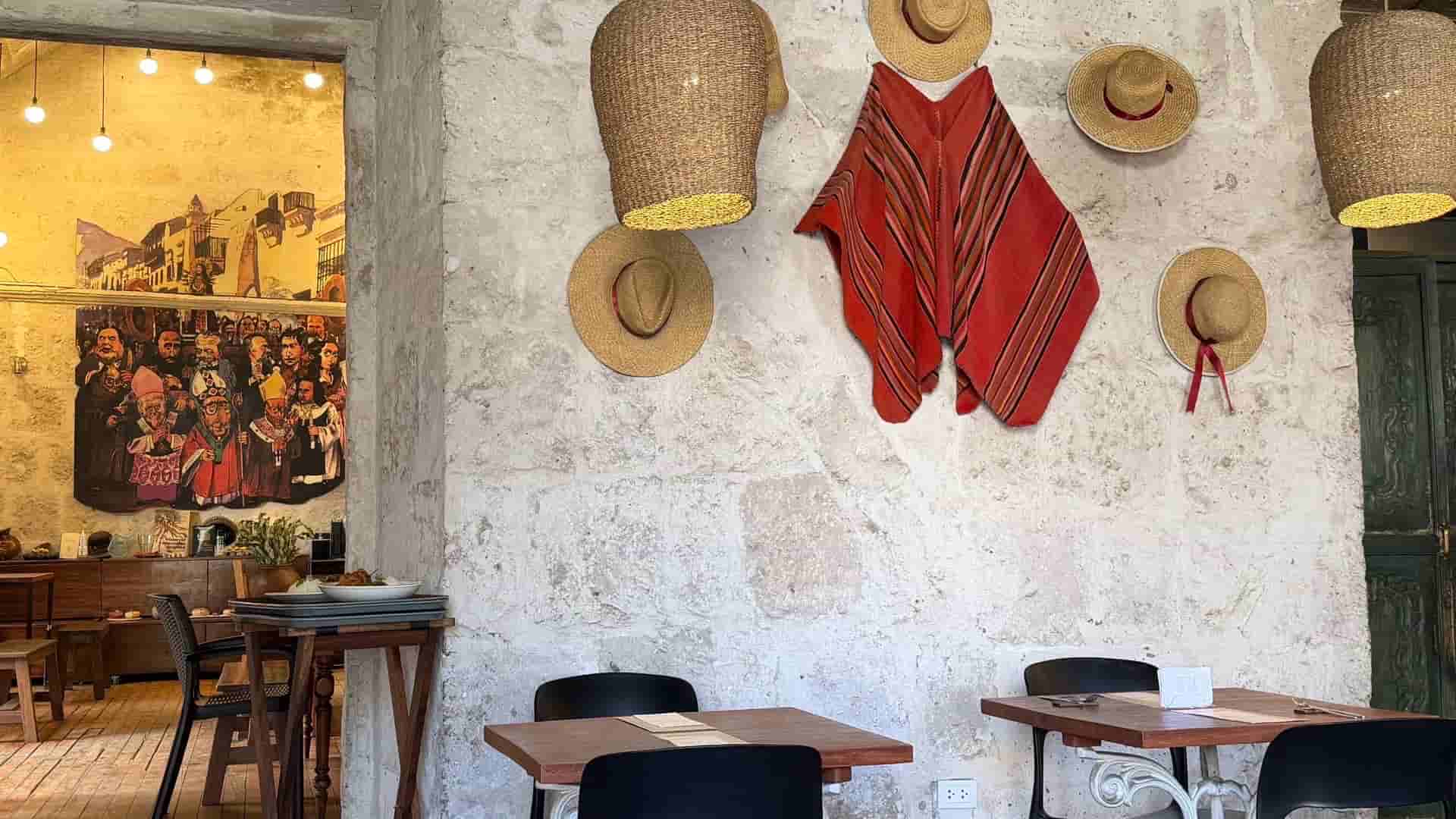 Traditional stone wall dining room decorated with woven ponchos and artisan straw hats.