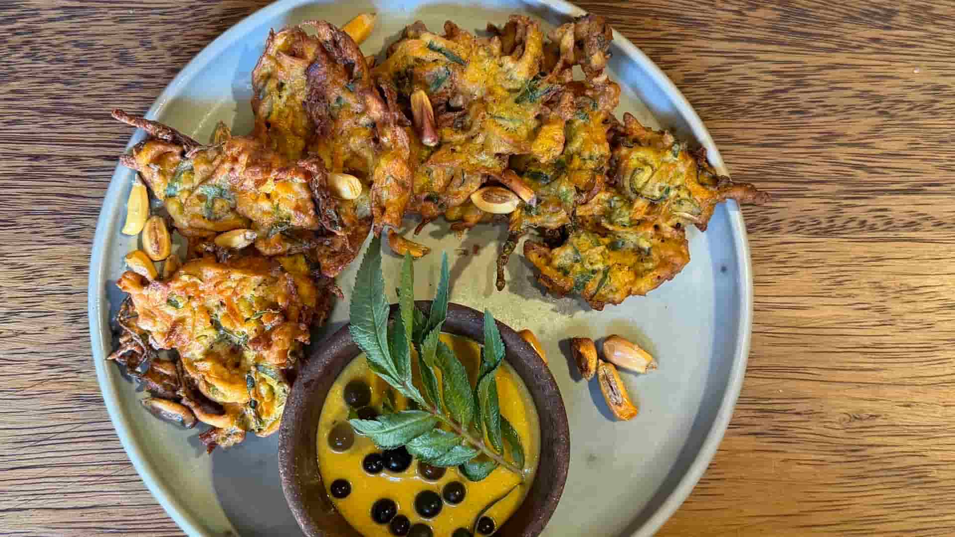 Fried vegetable fritters served with a rich dipping sauce and toasted native corn.