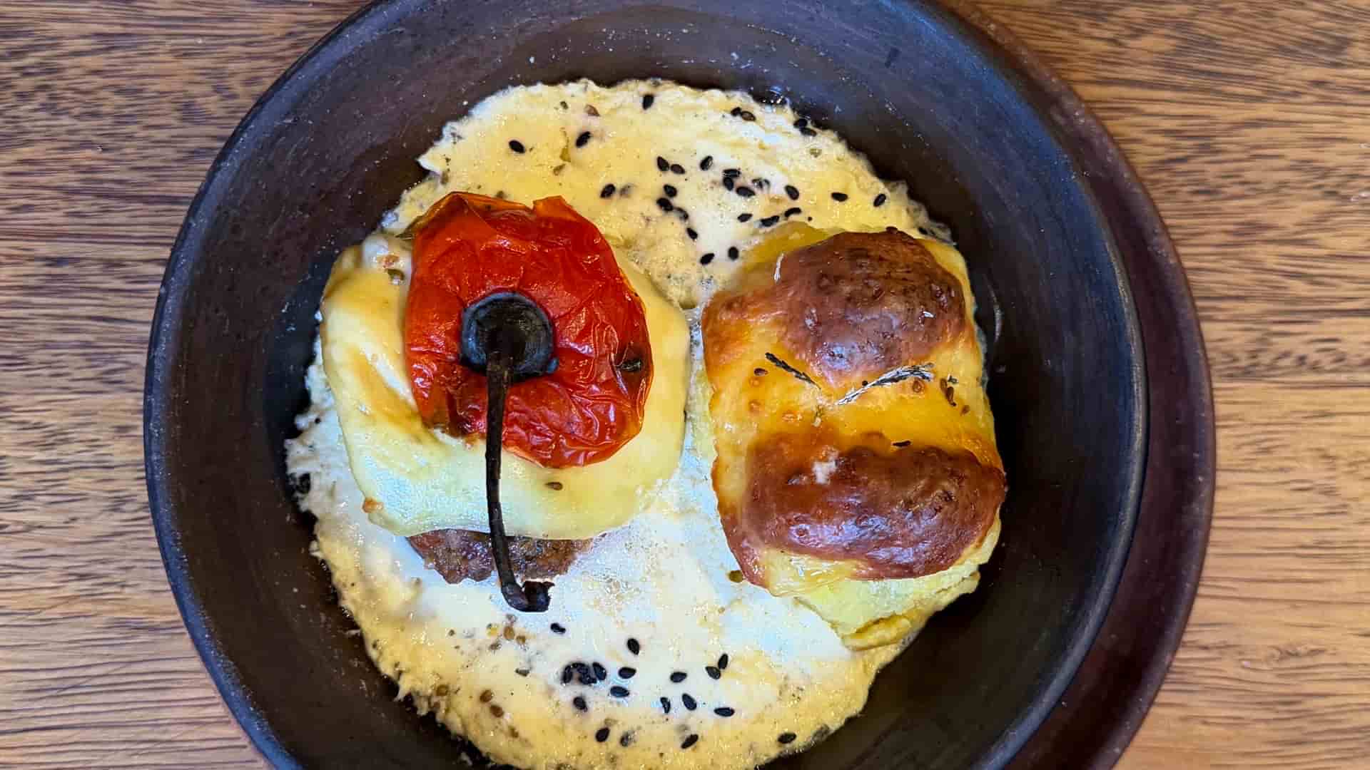 Savory stuffed pepper and potato dish baked with melted cheese in a ceramic bowl.