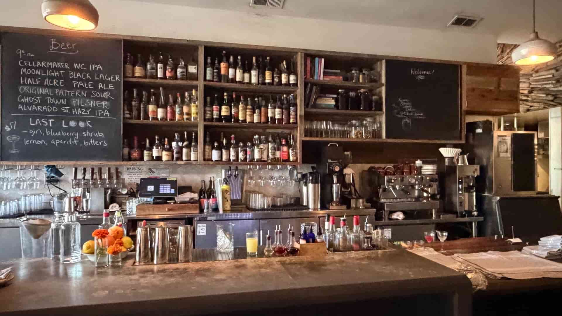 Industrial bar counter showcasing craft beer lists and stocked liquor shelves.