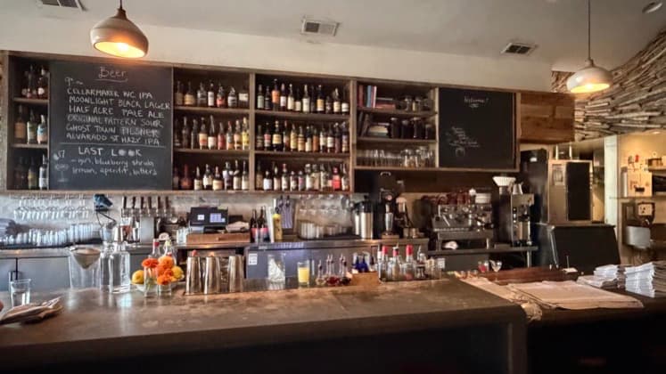 Industrial bar counter showcasing craft beer lists and stocked liquor shelves.